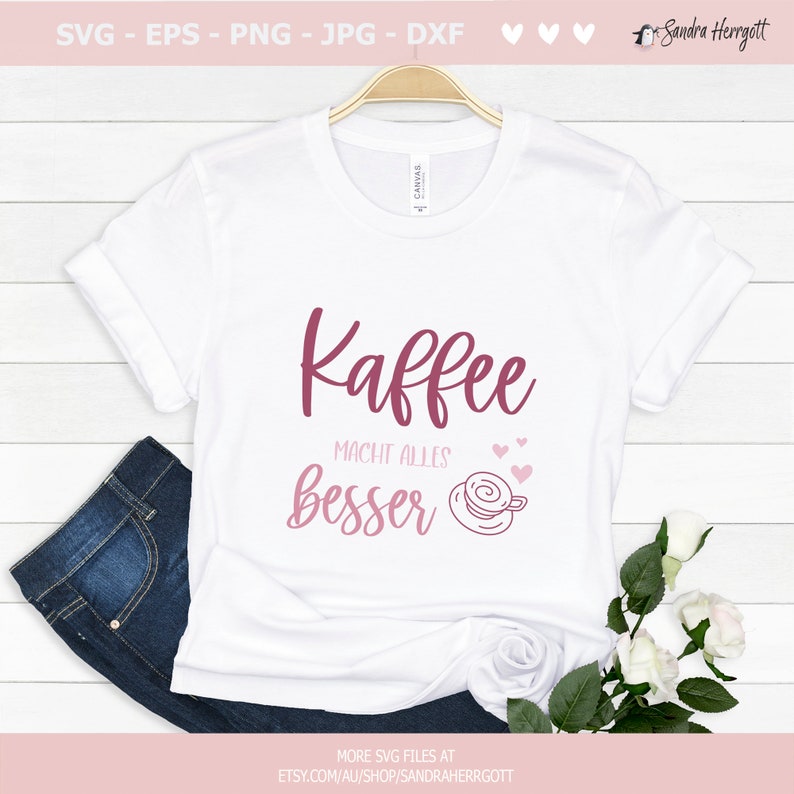 Pu&ograve; includere: Maglietta bianca con una grafica rosa che dice "Kaffee macht alles besser" con una tazza di caff&egrave; rosa e cuori.