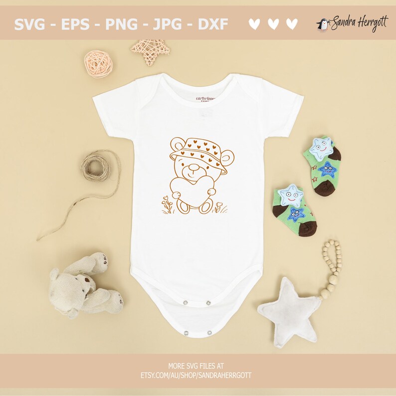 May include: A white baby onesie with a brown line drawing of a teddy bear wearing a hat with hearts on it. The teddy bear is holding a heart in its paws. The onesie is on a beige background with other baby items.