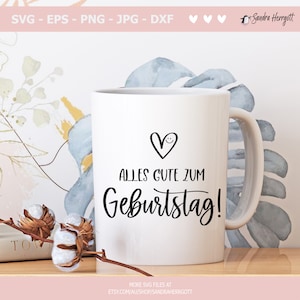 May include: White ceramic mug with a black handle. The mug has a black heart with a smiley face and the text "ALLES GUTE ZUM Geburtstag!" in black script.