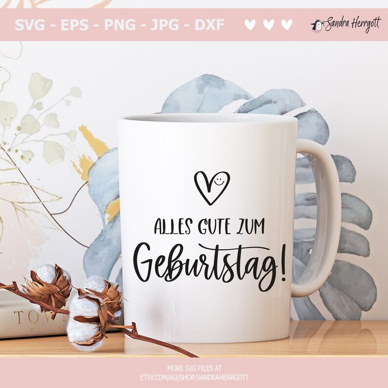 May include: White ceramic mug with a black handle. The mug has a black heart with a smiley face and the text "ALLES GUTE ZUM Geburtstag!" in black script.