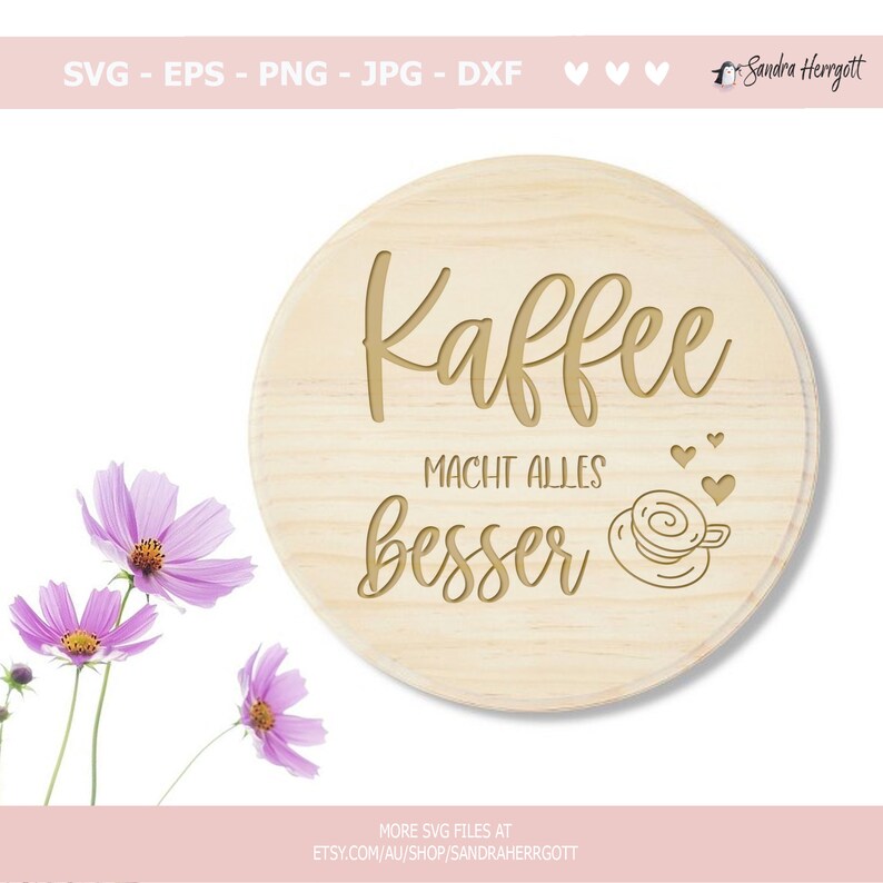Pu&ograve; includere: Un cartello rotondo in legno con il testo "Kaffee Macht Alles Besser" in lettere dorate. Sotto il testo &egrave; illustrata una piccola tazza di caff&egrave; con cuori.
