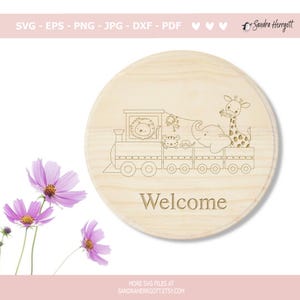 May include: A round wooden sign with a laser-etched train carrying various animals, including a lion, monkey, tiger, elephant, and giraffe. The word "Welcome" is etched below the train. The sign is surrounded by pink flowers.
