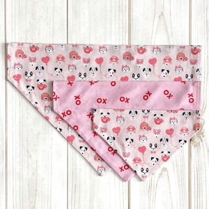 May include: Three pink dog bandanas with a pattern of dogs and hearts. The largest bandana has the text "XO" repeated across the bottom.