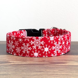 May include: Red dog collar with a white snowflake pattern.