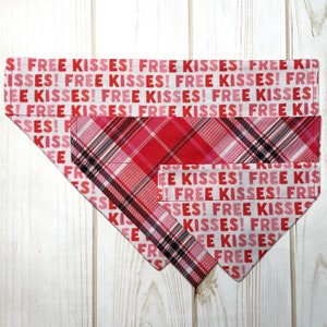 May include: Two dog bandanas with a pink and red plaid pattern and the text "Free Kisses!" repeated in pink on a white background.
