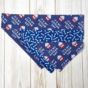 May include: Three blue dog bandanas with white bone and red cupcake patterns. The bandanas feature the text "It's My Gotcha Day".
