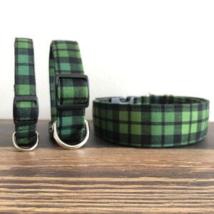 May include: Three green and black plaid dog collars of different sizes. The collars are made of fabric and have black plastic buckles.