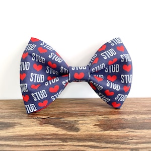 May include: A navy blue bow tie with red hearts and the word "STUD" repeated throughout the pattern.
