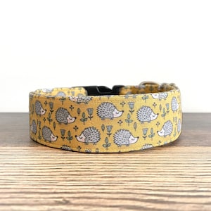 May include: A yellow dog collar with a repeating pattern of gray hedgehogs and green flowers.