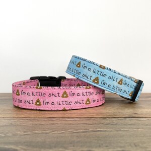 May include: Two dog collars, one pink and one light blue, with a repeating pattern of a poop emoji and the text "I'm a little shit".