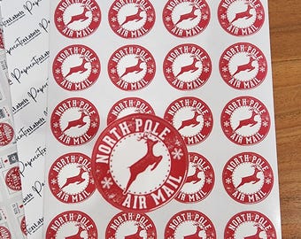 May include: A sheet of circular stickers featuring a red and white North Pole Air Mail design with a leaping reindeer silhouette, surrounded by small snowflake icons. The text North Pole Air Mail is printed in a circular border.