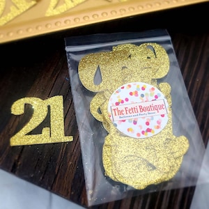 May include: Gold glitter number 21 cutouts in a clear plastic bag with a white circle sticker that says "The Fetti Boutique Balloons and Party Decor".