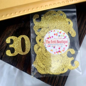 May include: Gold glitter confetti in the shape of the number 30. The confetti is packaged in a clear plastic bag with a white label that reads "The Fetti Boutique, Balloons and Party Decor".