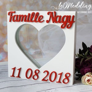 May include: White wooden box with a heart-shaped opening. The box has the words "Famille Nagy" and the date "11 08 2018" written in red.