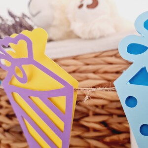 May include: A string of paper party decorations with a blue, yellow, and purple color scheme. The decorations are shaped like party hats and are connected by a twine string.