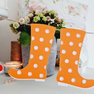 Könnte beinhalten: Eine Girlande aus orangefarbenen und roten Gummistiefeln mit weißen Punkten, die an einer Bindfadenkette hängen. Die Stiefel sind aus Papier und sind eine lustige Dekoration für eine Party oder Veranstaltung.