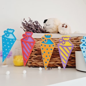 May include: A colorful paper garland with a string of cone-shaped party favors in blue, orange, purple, and yellow with different patterns.