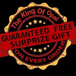 May include: A distressed, circular emblem with the text "The King Of Opal" in a black and red design. A red banner across the center reads "GUARANTEED FREE SURPRIZE GIFT ON EVERY ORDER". The emblem has a gold border and star accents.