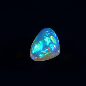 Könnte beinhalten: Ein tropfenförmiger Opal-Edelstein mit einem durchscheinenden weißen Körper und einem lebendigen Spiel der Farben in Blau, Grün und Orange.