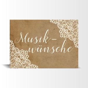 May include: A brown paper card with white lace trim and the text "Musik-w&uuml;nsche" in white cursive writing.