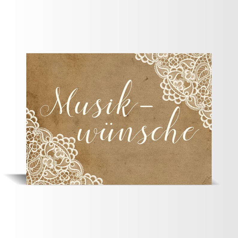 May include: A brown paper card with white lace trim and the text "Musik-w&uuml;nsche" in white cursive writing.