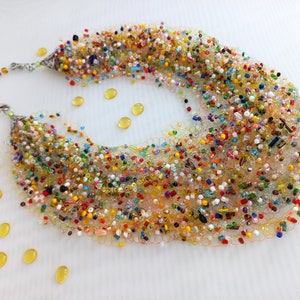 May include: Multicoloured beaded necklace with a silver clasp. The beads are of various shapes and sizes, and the necklace is made of a fine mesh material.