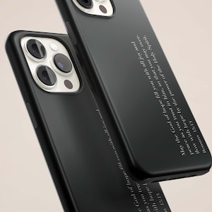 May include: Two black phone cases with a matte finish are shown. The cases have a camera cutout and feature white text that reads "May the God of hope fill you with all joy and peace as you trust in him..." Romans 15:13.