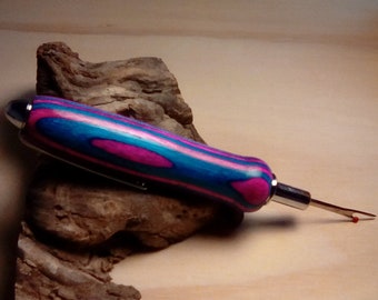 May include: A close-up of a pink, blue, and white wood handled seam ripper with a silver metal blade.