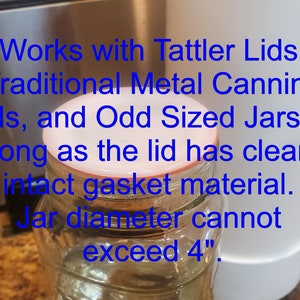 May include: A clear glass jar with a white lid. The lid has a red rubber gasket. The text on the image reads: "Works with Tattler Lids, Traditional Metal Canning Lids, and Odd Sized Jars so long as the lid has clean intact gasket material. Jar diameter cannot exceed 4"."