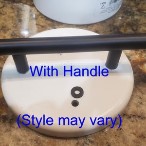 May include: White ceramic lid with a black metal handle. The lid has a small black rubber ring and a hole in the center. The text "With Handle (Style may vary)" is printed on the lid.
