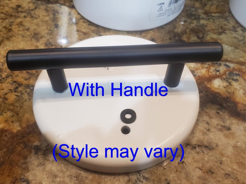 May include: White ceramic lid with a black metal handle. The lid has a small black rubber ring and a hole in the center. The text "With Handle (Style may vary)" is printed on the lid.
