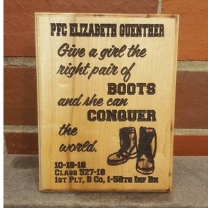May include: A wooden sign with the text "PFC ELIZABETH GUENTHER Give a girl the right pair of BOOTS and she can CONQUER the world."  The sign also includes the text "10-18-18 CLASS 527-18 1ST PLT, D Co, 1-58TH INF BN".