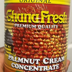 May include: A yellow and red can of Ghana Fresh Original Palm Nut Cream Concentrate Sauce Graine. The can features a picture of palm nuts.