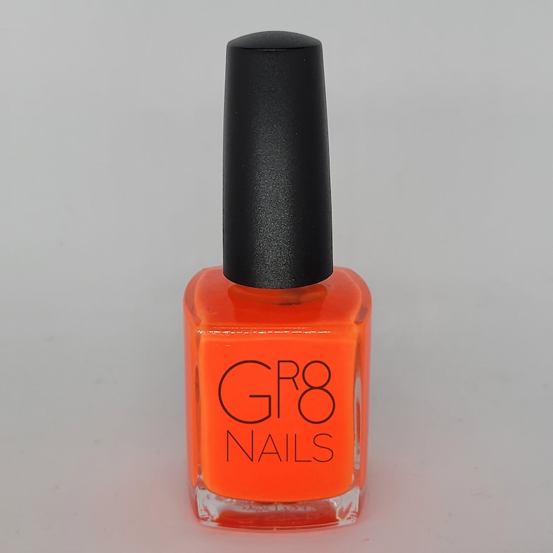 May include: A bottle of bright orange nail polish with a black cap. The bottle is square with rounded edges and features the text "GR8 NAILS" in black. The nail polish is a vibrant, solid color.