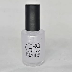 May include: Clear nail polish bottle with a black cap. The bottle has the text "GR8 NAILS" printed in black. The polish appears to be clear and the bottle is sitting on a white surface.
