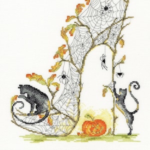 Peut inclure: Un chat noir est assis sur une chaussure à talon haut recouverte de toiles d'araignées avec une citrouille sculptée en forme de visage souriant devant lui. Un autre chat noir grimpe à une vigne avec des toiles d'araignées.