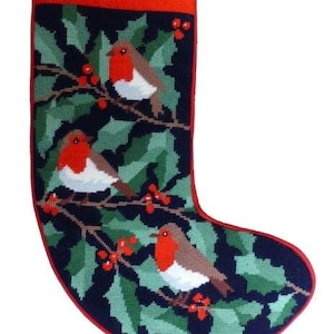 Könnte beinhalten: Ein Weihnachtsstrumpf mit rotem Bund und Besatz. Das Hauptteil zeigt ein Gobelin-Design von Rotkehlchen auf Stechpalmenzweigen mit roten Beeren, vor einem dunkelblauen Hintergrund. Inklusive einer Schlaufe zum Aufhängen.