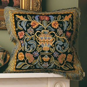 May include: A black velvet pillow with a gold fringe border features an embroidered design of a vase with flowers and leaves. The vase is yellow, blue, and orange, and the flowers are red, orange, yellow, blue, and purple.
