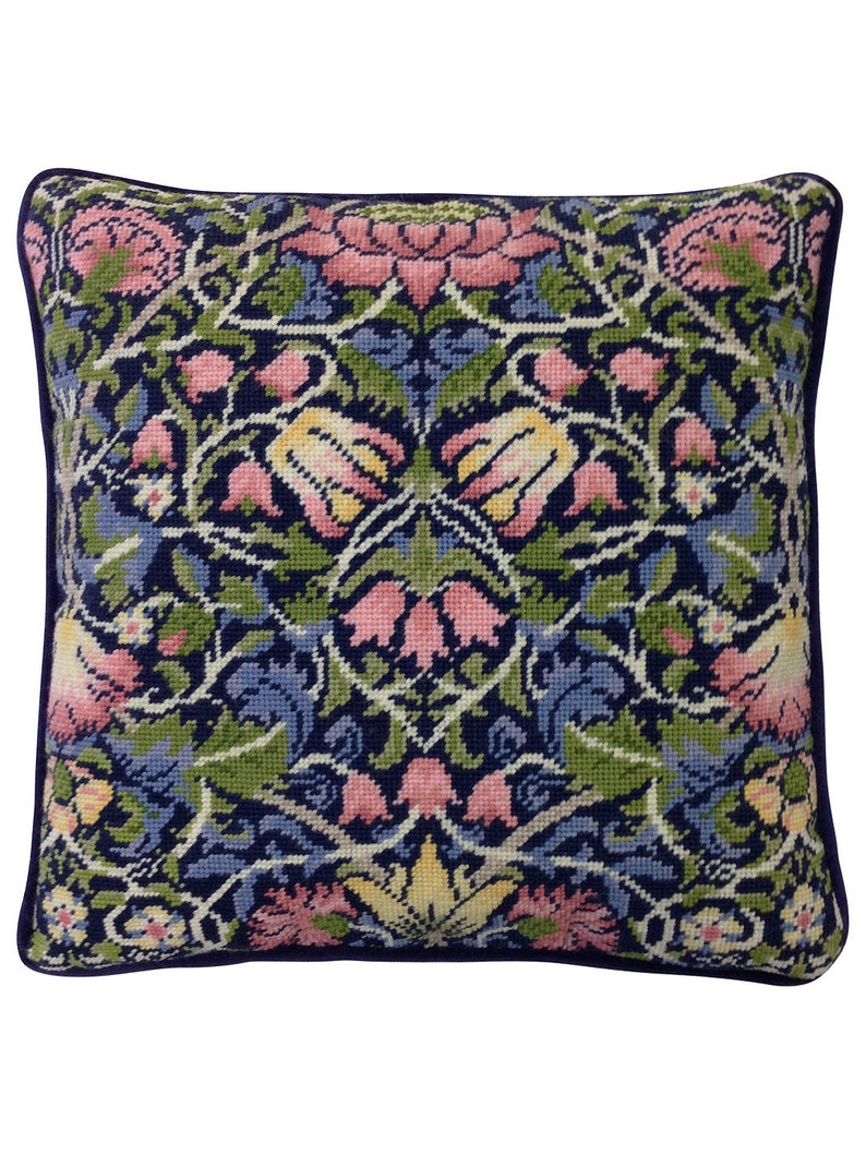 May include: A square pillow with a floral pattern in shades of pink, yellow, green, and blue on a dark blue background. The pillow has a dark blue border.