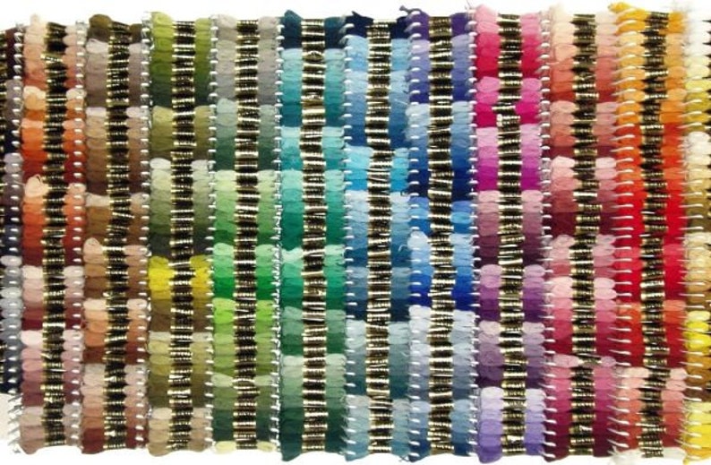 Puede incluir: Una vibrante exhibici&oacute;n de hilo de bordar en una amplia gama de colores. Los hilos est&aacute;n dispuestos en filas verticales, mostrando un degradado de tonos que van desde naranjas y amarillos c&aacute;lidos hasta azules y verdes fr&iacute;os, y terminando con rosas y rojos. Cada color est&aacute; cuidadosamente organizado.