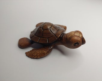May include: A small, hand-carved wooden turtle figurine with a brown finish. The turtle has a detailed shell and a realistic face.