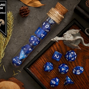 May include: A set of blue and white dice with a cobalt marble finish, in a glass test tube with a cork stopper. The dice are numbered 1 through 20. The dice are on a wooden tray with a dragon figurine.