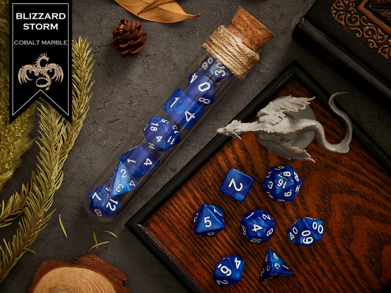 May include: A set of blue and white dice with a cobalt marble finish, in a glass test tube with a cork stopper. The dice are numbered 1 through 20. The dice are on a wooden tray with a dragon figurine.