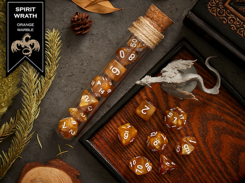 May include: A set of orange marble dice with white numbers in a glass test tube. The dice are in a wooden box with a miniature dragon figurine. The box has a dark brown wood grain finish.