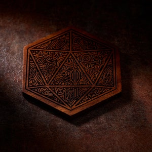 Puede incluir: Un posavasos de madera con forma de dado de 20 caras con diseños intrincados y el número "20" en el centro.