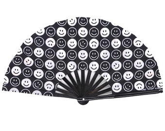 May include: Black folding fan with a white smiley face pattern. The fan has a black handle and the text "ONE DROP RAVE" is printed on the bottom right corner.