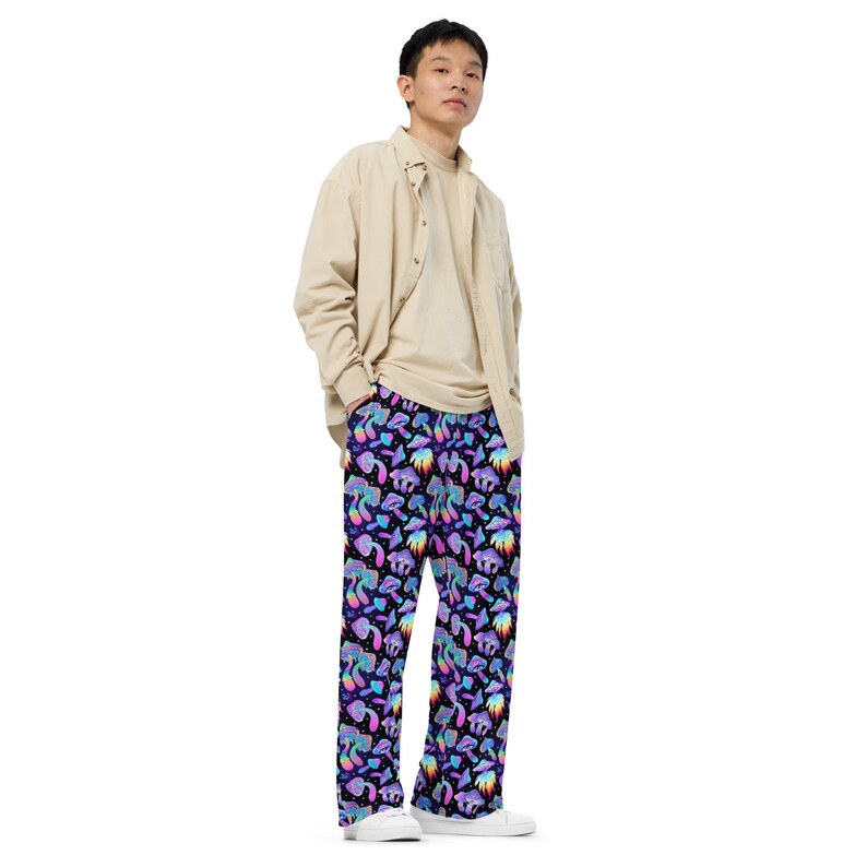 May include: A person wearing a light brown button-down shirt and black trousers with a colourful mushroom print.