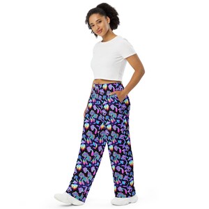 May include: Wide-leg trousers with a psychedelic print of colourful mushrooms on a black background. The trousers have a relaxed fit and a comfortable elastic waistband.