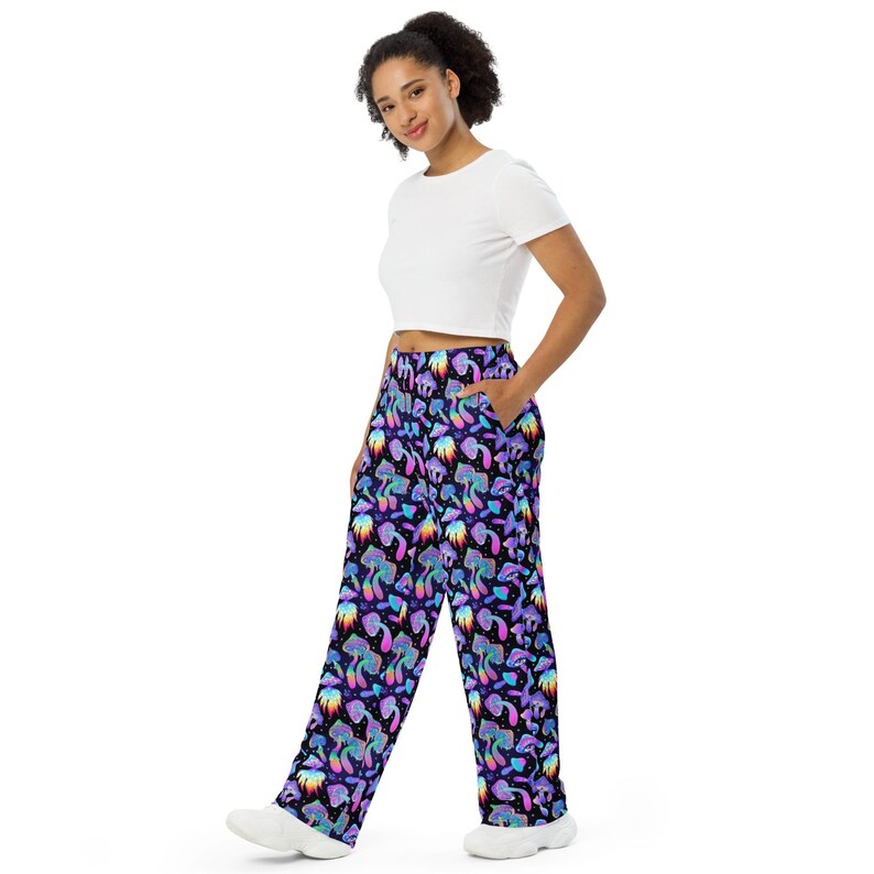 May include: Wide-leg trousers with a psychedelic print of colourful mushrooms on a black background. The trousers have a relaxed fit and a comfortable elastic waistband.