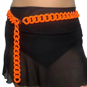 The model showcases a Colored Chunky Chain Belt in neon orange, adding a stylish touch to her festival outfit.